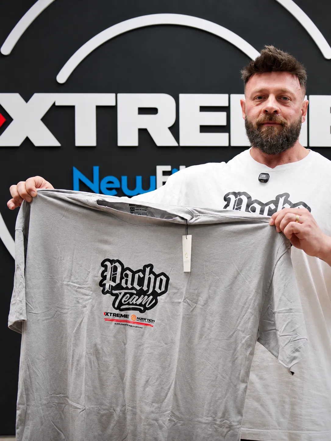 Fabrício Pacholok segurando a camiseta Pacho Team em frente ao logo Xtreme